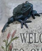 Bronze frog sculpture on a stone with 'Welcome' engraving