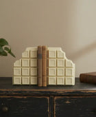 Decorative bookends shaped like a chocolate bar on a wooden surface with books and a plant.