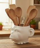 White ceramic container with wooden spoons on a kitchen counter