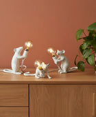 Three white mouse-shaped lamps with light bulbs on a book