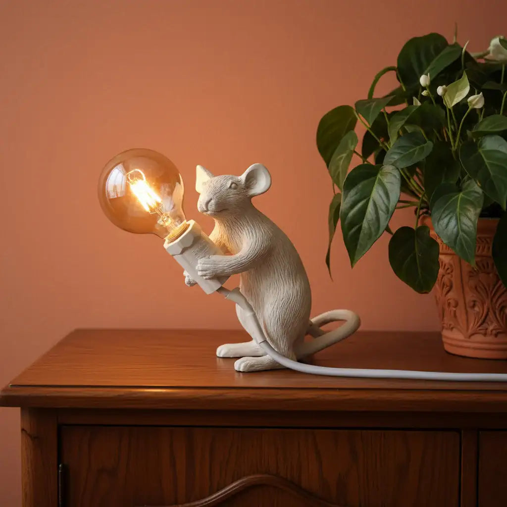 White mouse-shaped lamp holding a light bulb next to a vase of flowers on a neutral background