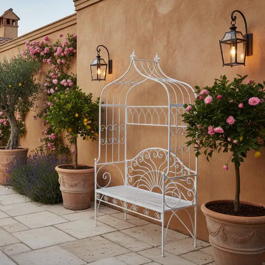 Decorative white metal bench with floral and potted plants in an outdoor setting.