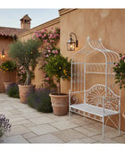 Patio with decorative white bench, potted plants, and a building in the background