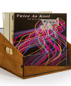 A wooden record holder with a black mesh front, holding several vinyl records, including the album 'Twice As Kool' by The Kool & Gang.