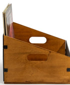 A wooden magazine rack with a warm medium-brown finish, featuring two oval cutouts for handles and black metal corner brackets, shown holding a few books on a white background.