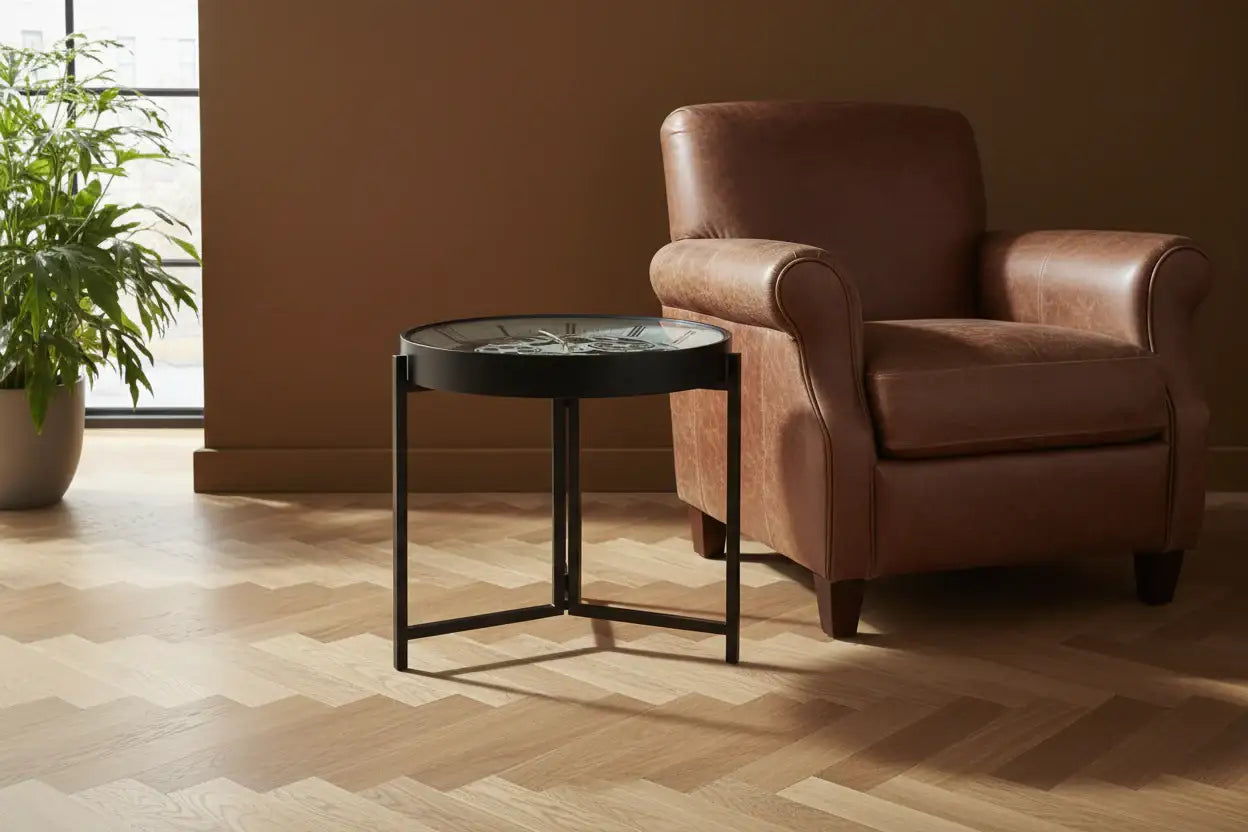 Brown leather armchair and round black table in a room with a plant and window.