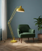 Green armchair with a yellow floor lamp in a room with a plant and window.