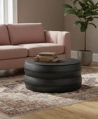 Living room with pink sofa, round black coffee table, and potted plant.