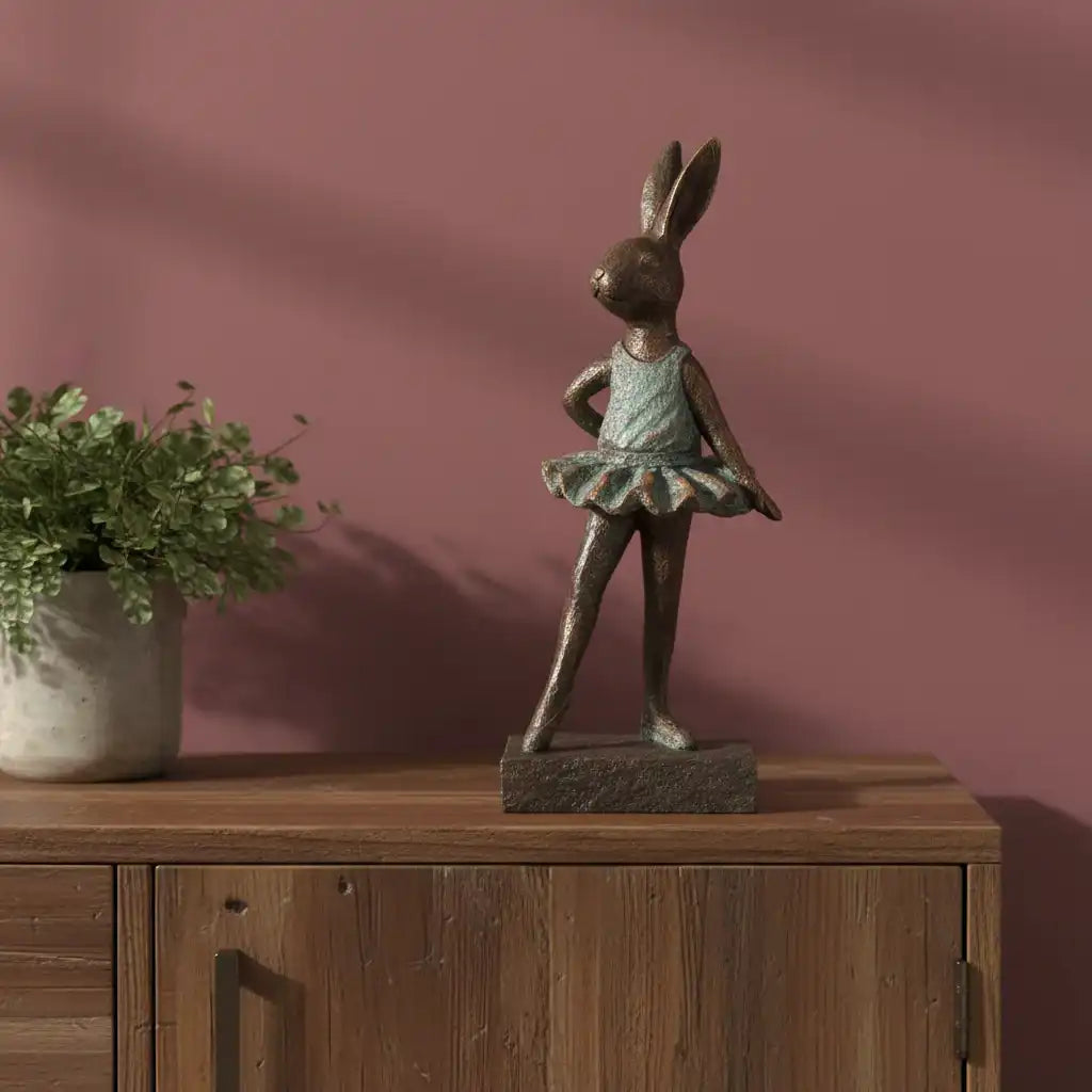 Bronze rabbit sculpture on a wooden surface with a pink wall background