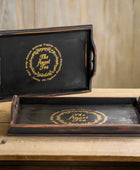 Two black trays with gold text on a white background