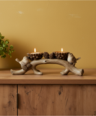 Decorative candle holder with candles on a wooden surface against a yellow wall.