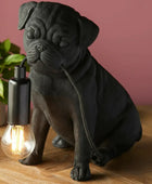 Black dog-shaped lamp with a lit bulb on a wooden surface