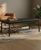 Black metal coffee table with decorative items in a room with a plant and patterned rug.