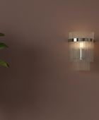 Wall-mounted light fixture casting a shadow on a wall next to a potted plant.