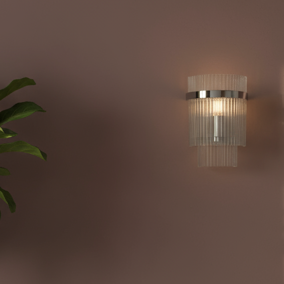 Wall-mounted light fixture casting a shadow on a wall next to a potted plant.