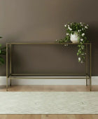 Modern console table against a brown wall with a plant on the left.
