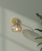 Wall-mounted light fixture with a glass shade on a neutral wall.