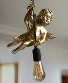 Gold cherub figure with a light bulb inside against a neutral background