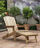 Wooden lounge chair on a patio with plants and a stone wall in the background
