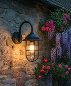 Outdoor wall light fixture on a stone wall with flowers in the background