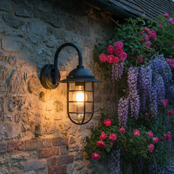 Outdoor wall light fixture on a stone wall with flowers in the background