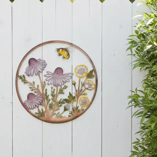 Decorative metal wall art with flowers and a bee on a white wooden background
