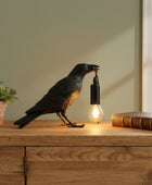 Decorative lamp shaped like a crow with a light bulb in its mouth on a neutral background