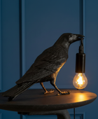 Decorative crow lamp with a light bulb on a dark background