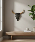 Decorative bull skull on a wall above a wooden bench with a plant and small decor items.