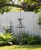 Decorative wind chime hanging from a tree branch in a garden setting.