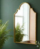 Gold-framed mirror on a green wall with plants around