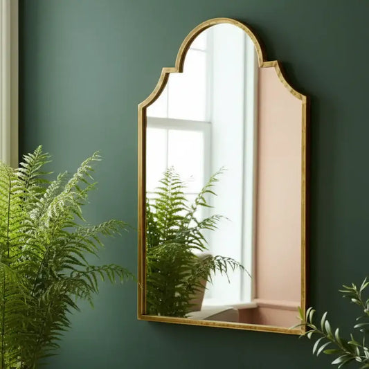 Gold-framed mirror on a green wall with plants around