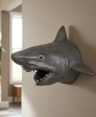 Shark head wall decoration in a room with a plant and window.