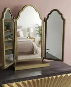 Tri-fold vanity mirror on a dresser with a bedroom in the reflection