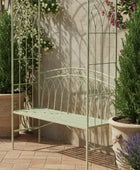 Decorative metal bench with floral arches and potted plants in a garden setting.