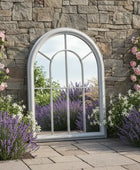 Arched garden mirror with flowers and a stone wall background
