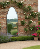 Garden scene with a brick wall, mirror, and potted plants