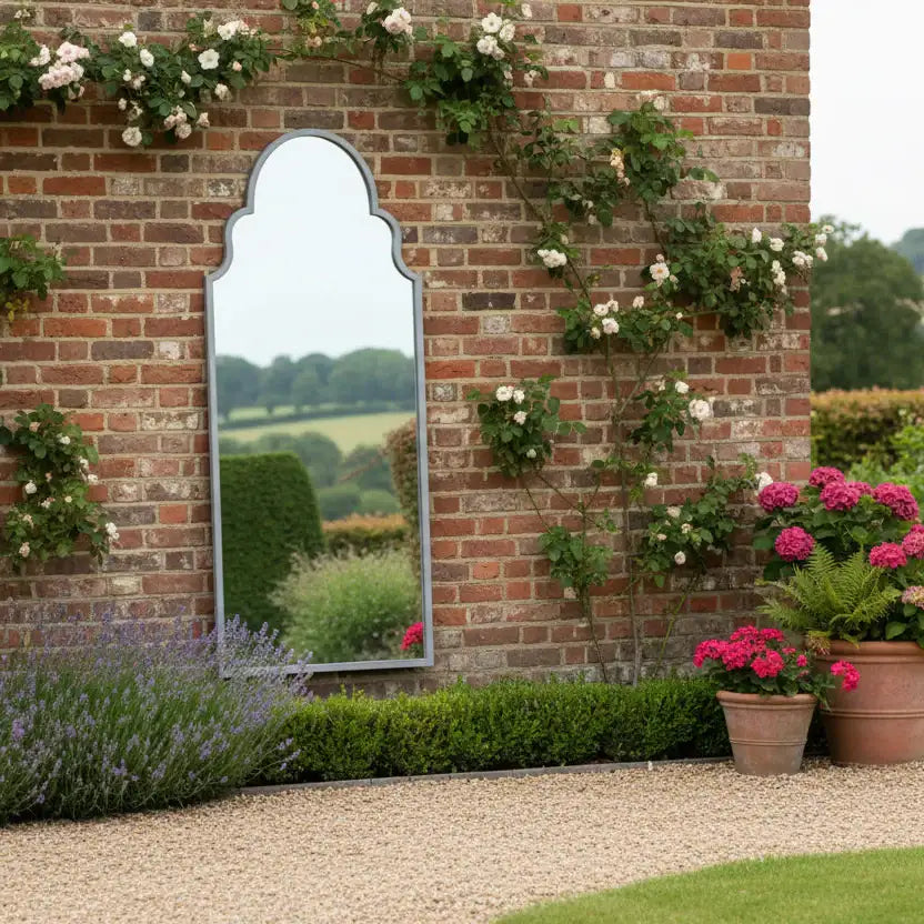 Garden scene with a brick wall, mirror, and potted plants