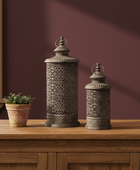 Two ornate lanterns on a wooden surface with a maroon wall in the background