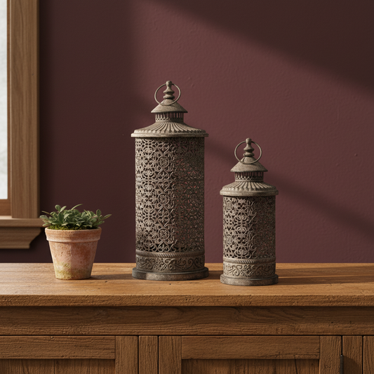 Two ornate lanterns on a wooden surface with a maroon wall in the background