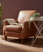 Brown leather armchair in a room with a plant and small table.