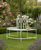 White metal garden bench and table set in a lush garden with flowers and lavender.