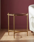 Gold side table with glass top in a room with a white chair and purple wall.