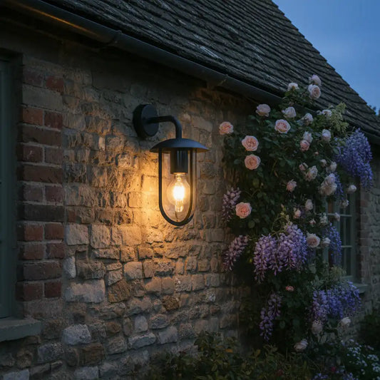 Outdoor wall light fixture on a stone building with flowers in the background
