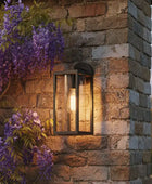 Outdoor wall light fixture on a stone wall with purple flowers in the foreground
