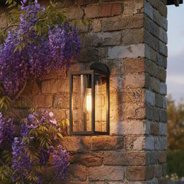 Outdoor wall light fixture on a stone wall with purple flowers in the foreground