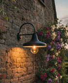Outdoor wall light fixture on a stone wall with flowers in the background