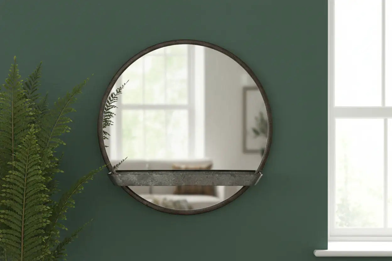Round mirror on a green wall with a plant to the left
