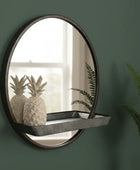 Round wall mirror with a shelf on a green wall, featuring decorative pineapples.