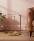 Gold side table with a plant and brown sofa against a pink wall